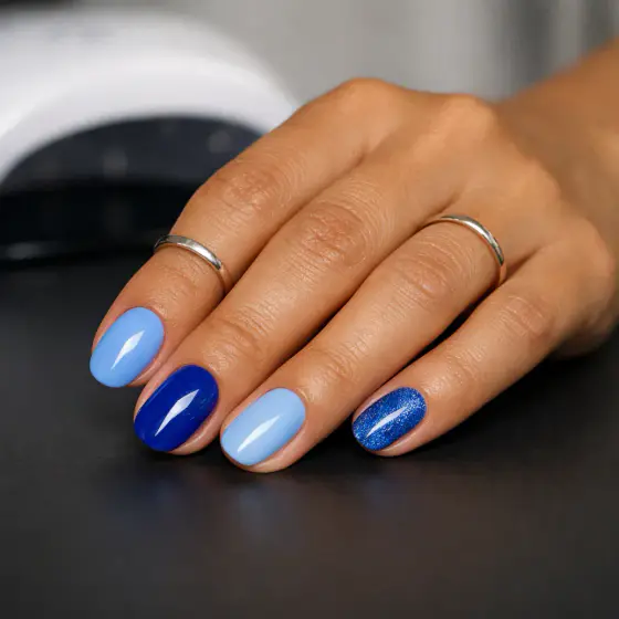 Uñas azules cortas con una uña de glitter azul