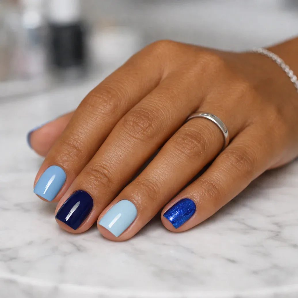 Uñas cortas azules con una uña de glitter discreto